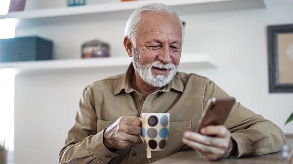 Elderly person looking at a smartphone and holding a cup. Elderly person looking at a smartphone and holding a cup.