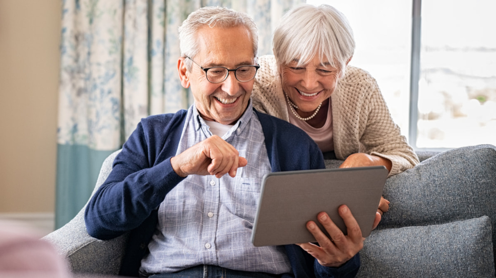 An elderly couple looking at a tablet together